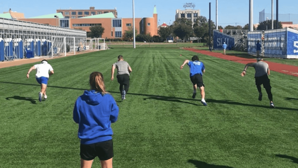 athletes sprinting with coach on field
