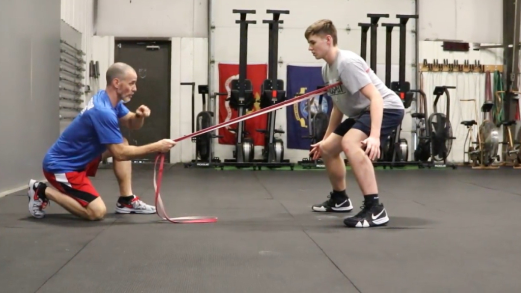 Using an elastic band to resist an athlete with hip turn
